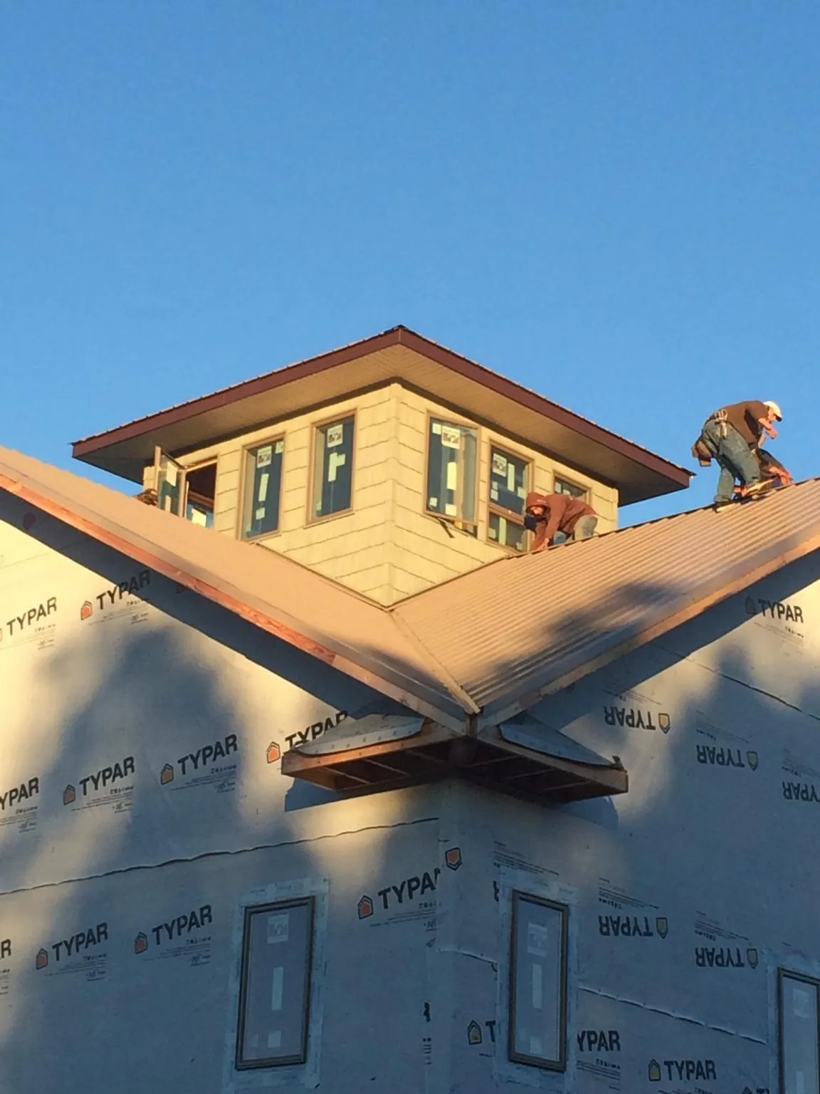 Roofers working around a rooftop cupola on a new metal roof at sunset — Roof Waterproofing in Scranton by Roofing Brothers